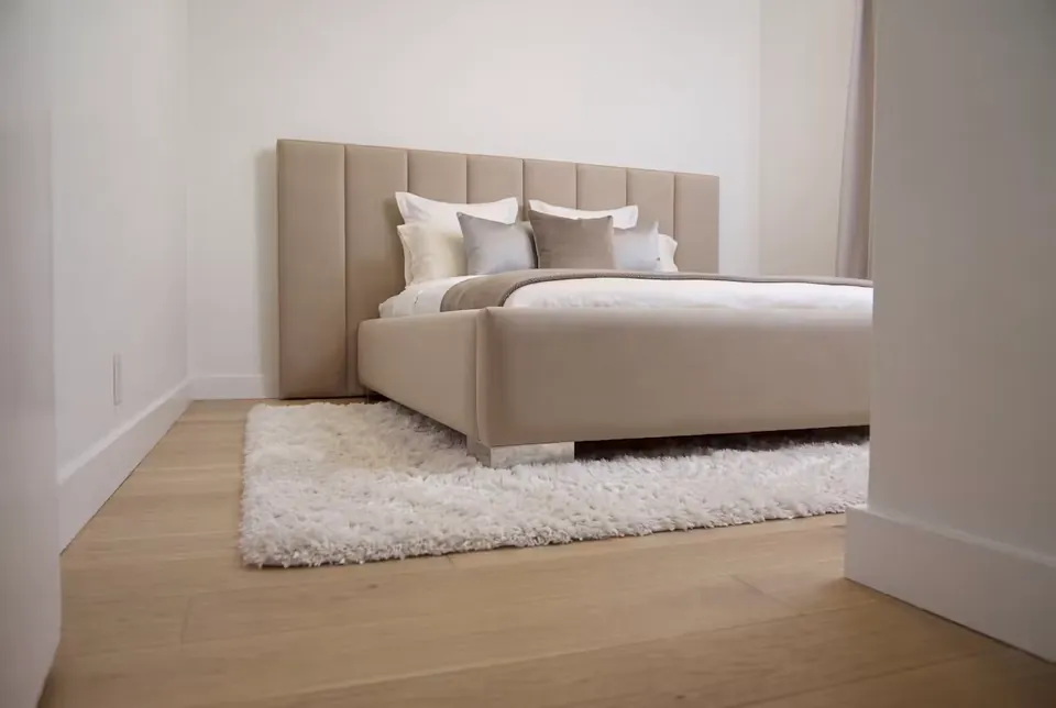 Wide view of the beige channel bed seen through the bedroom doorway.