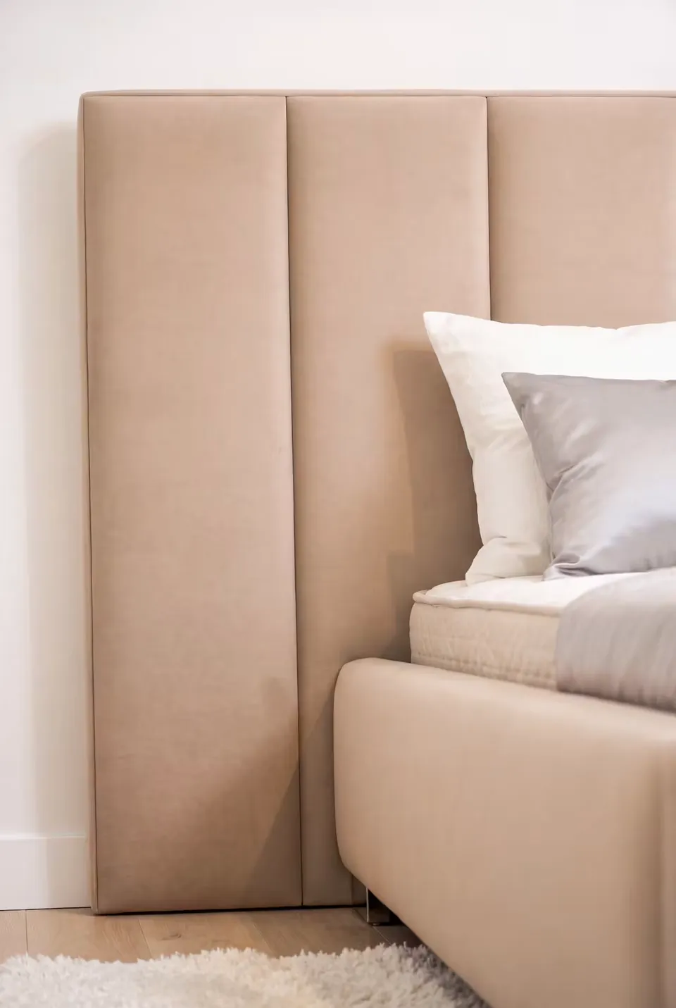 Detail of the beige headboard channels meeting the plain upholstered side rail.