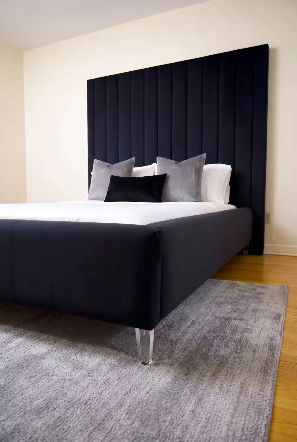 Angled view of the black bed frame and tall narrow headboard channels on a grey rug