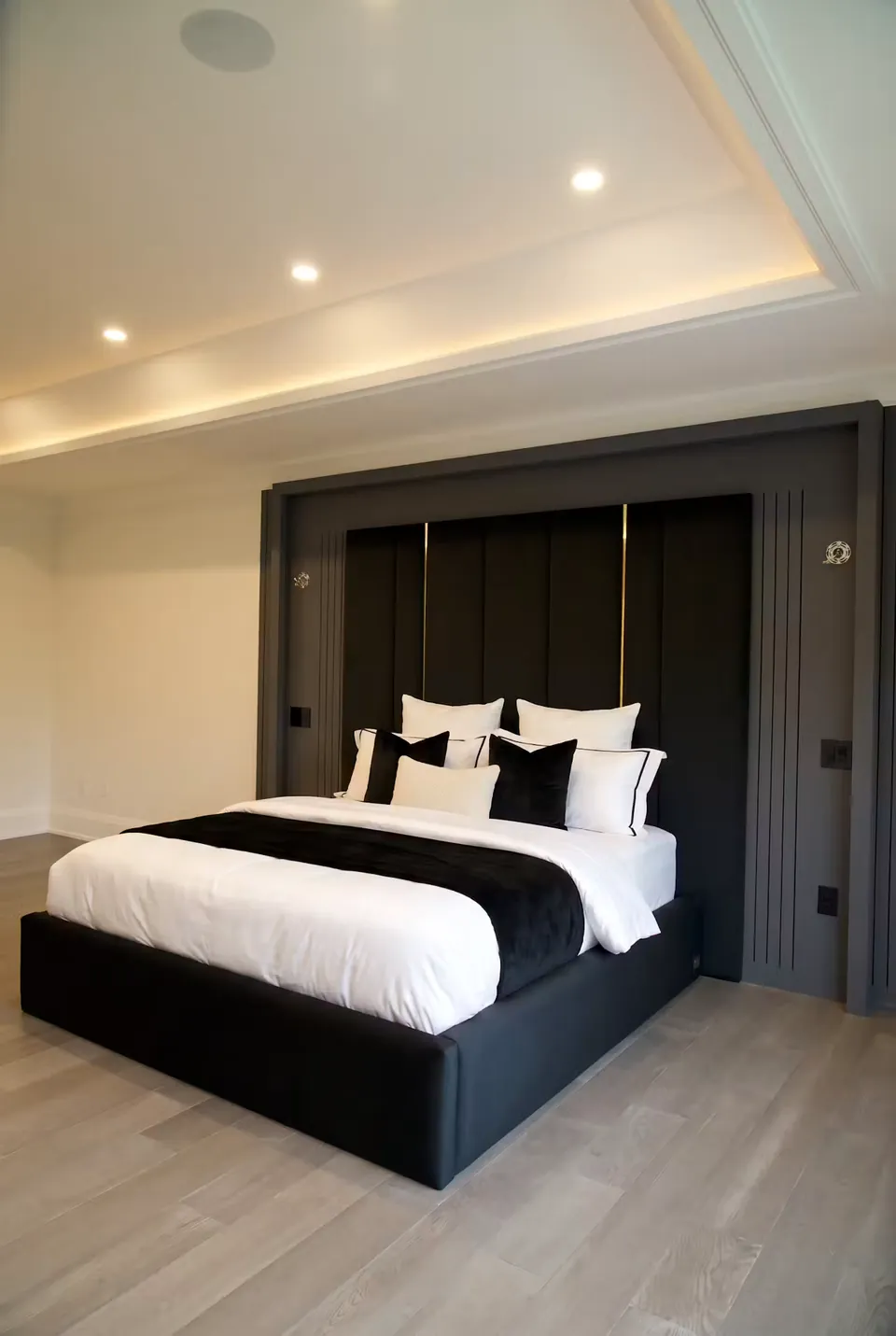 Full angled view of a black bed beneath black and gold wall channels with a grey surround.
