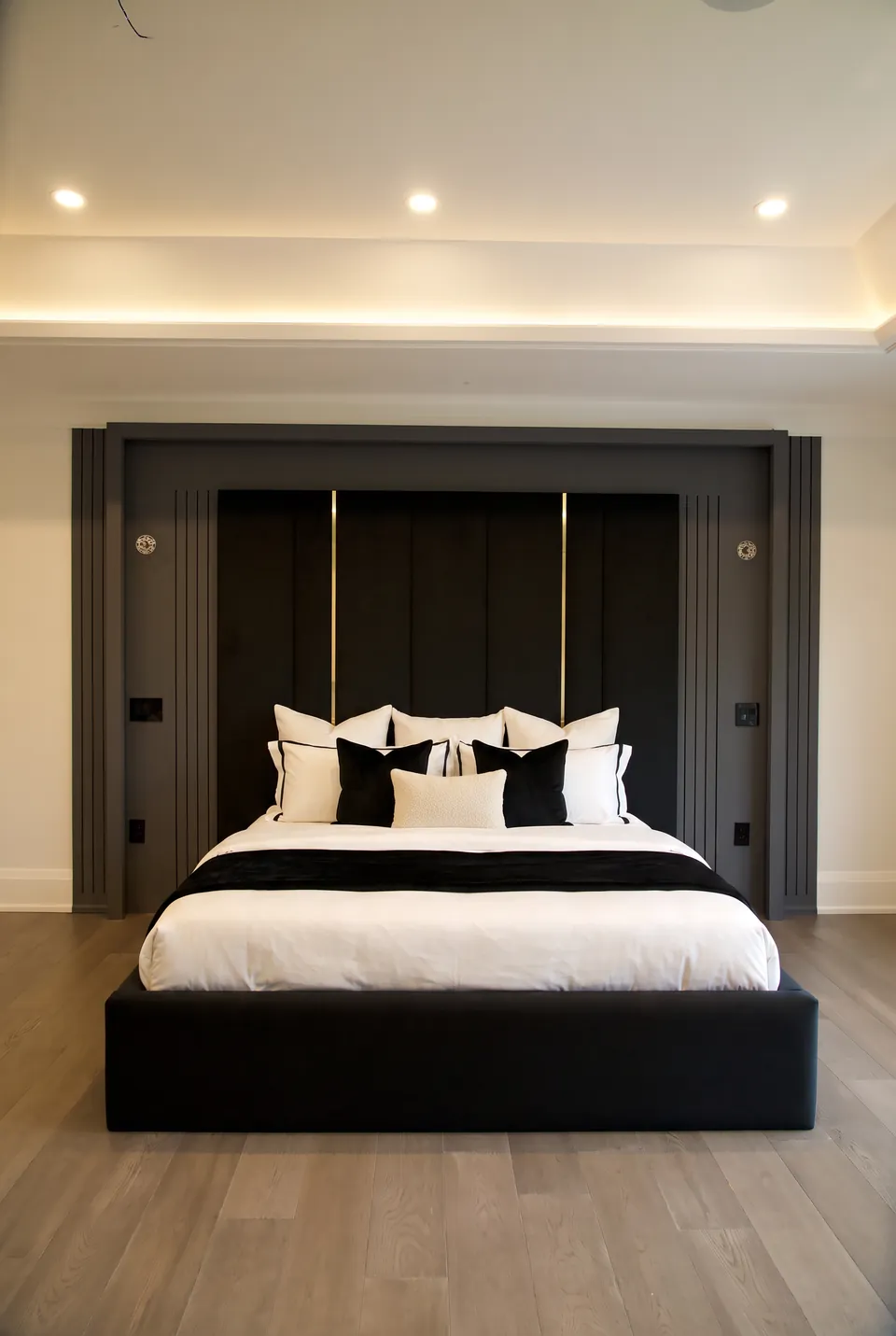Front view of black upholstery with slim gold vertical lines and white bedding.
