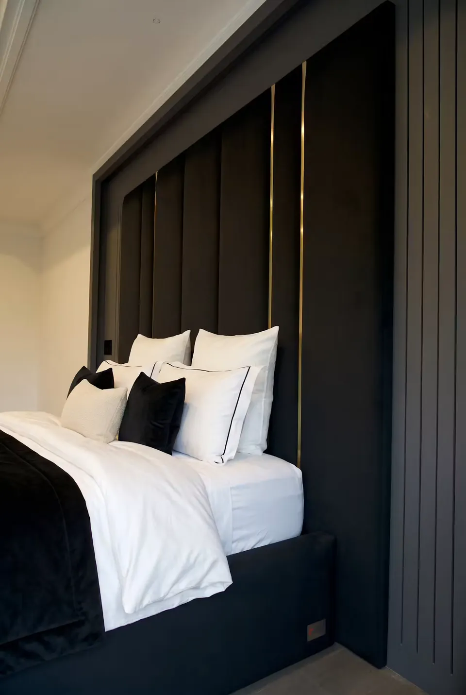 Close side view of black wall padding, gold trim and grey fluted edging.