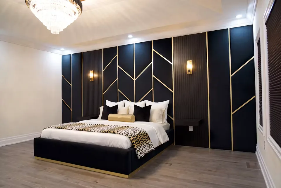Full wide view of a black upholstered bed beneath gold-lined geometric panels and dark fluted sections.