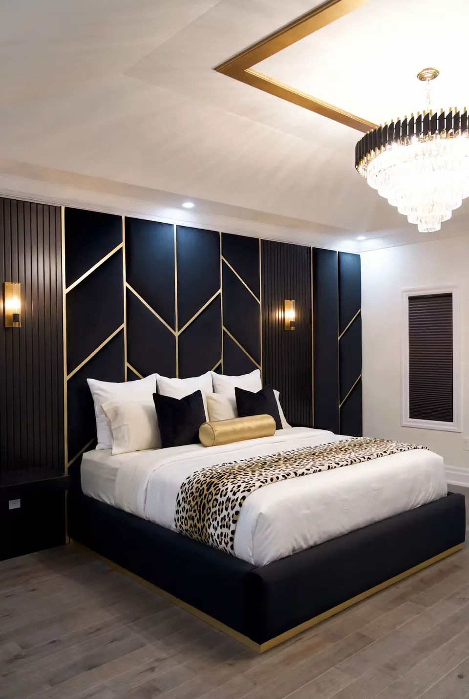 Full angled view of the dark bed, gold-edged base and tall black padded wall.