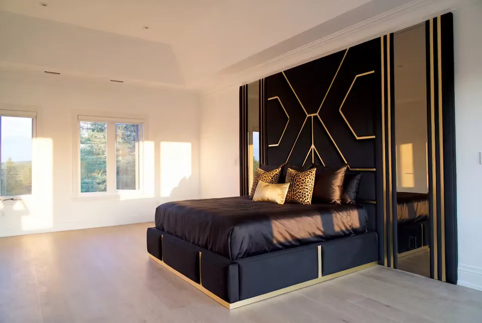 Full black bed beneath gold crossing lines and mirrored wall sides