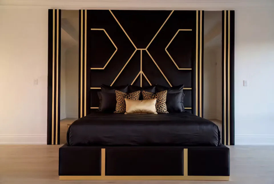 Front view of the black bed with gold-trimmed frame and angular wall lines