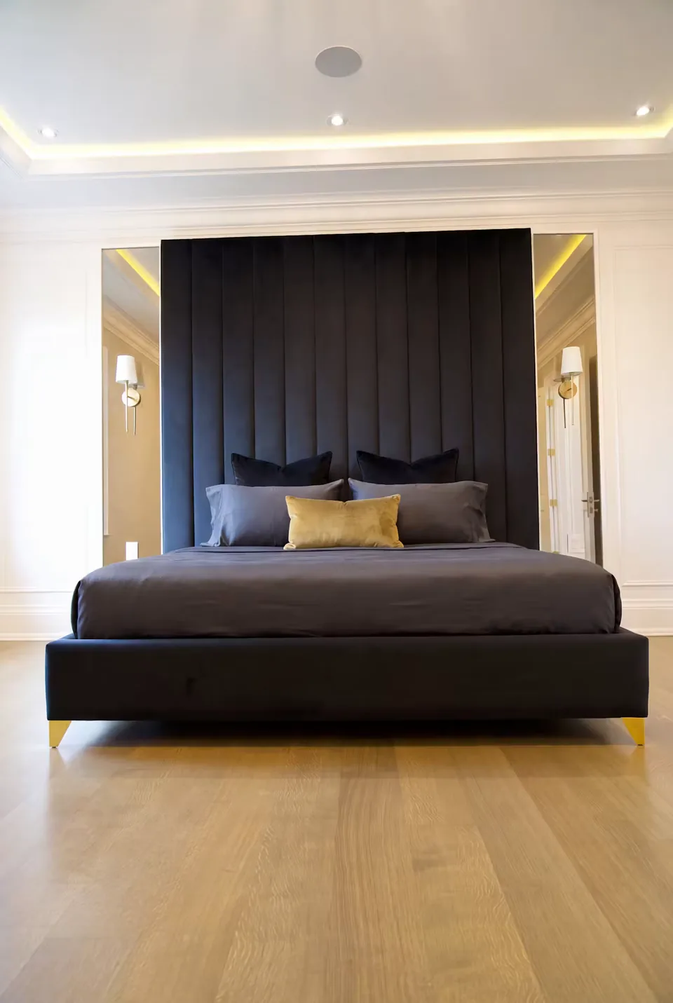 Front view of a black upholstered bed with tall channels and mirrored side panels