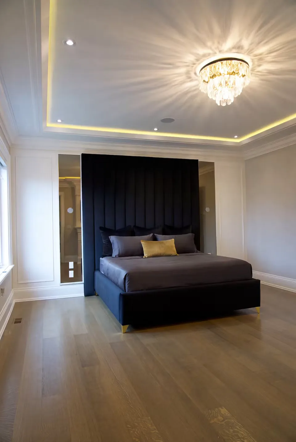 Full bedroom view of the black channelled wall under a chandelier