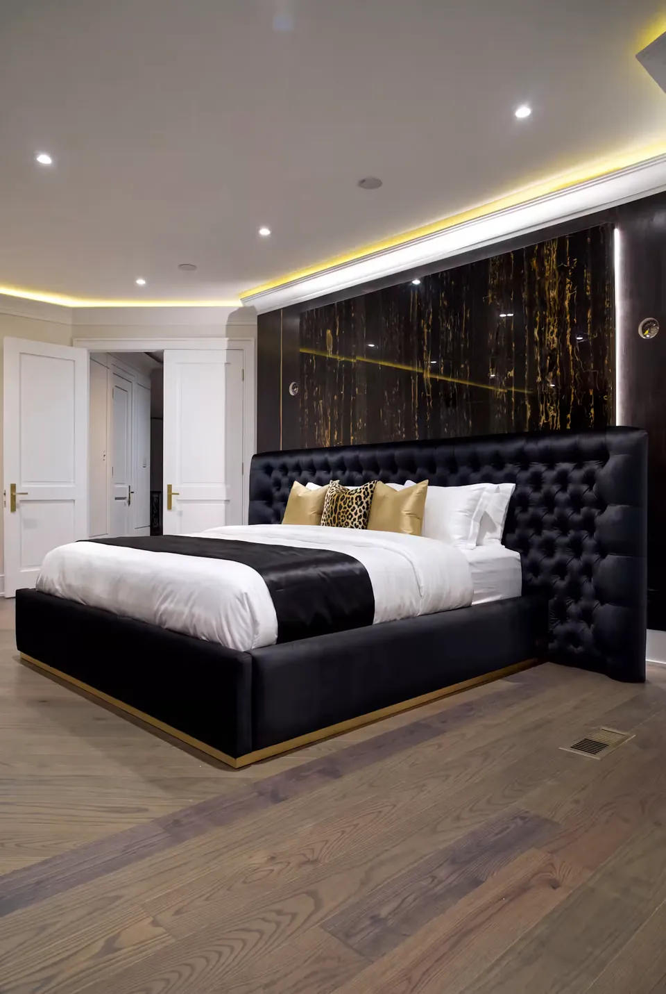 Full angled view of the black tufted bed with white bedding and a gold-edged base.
