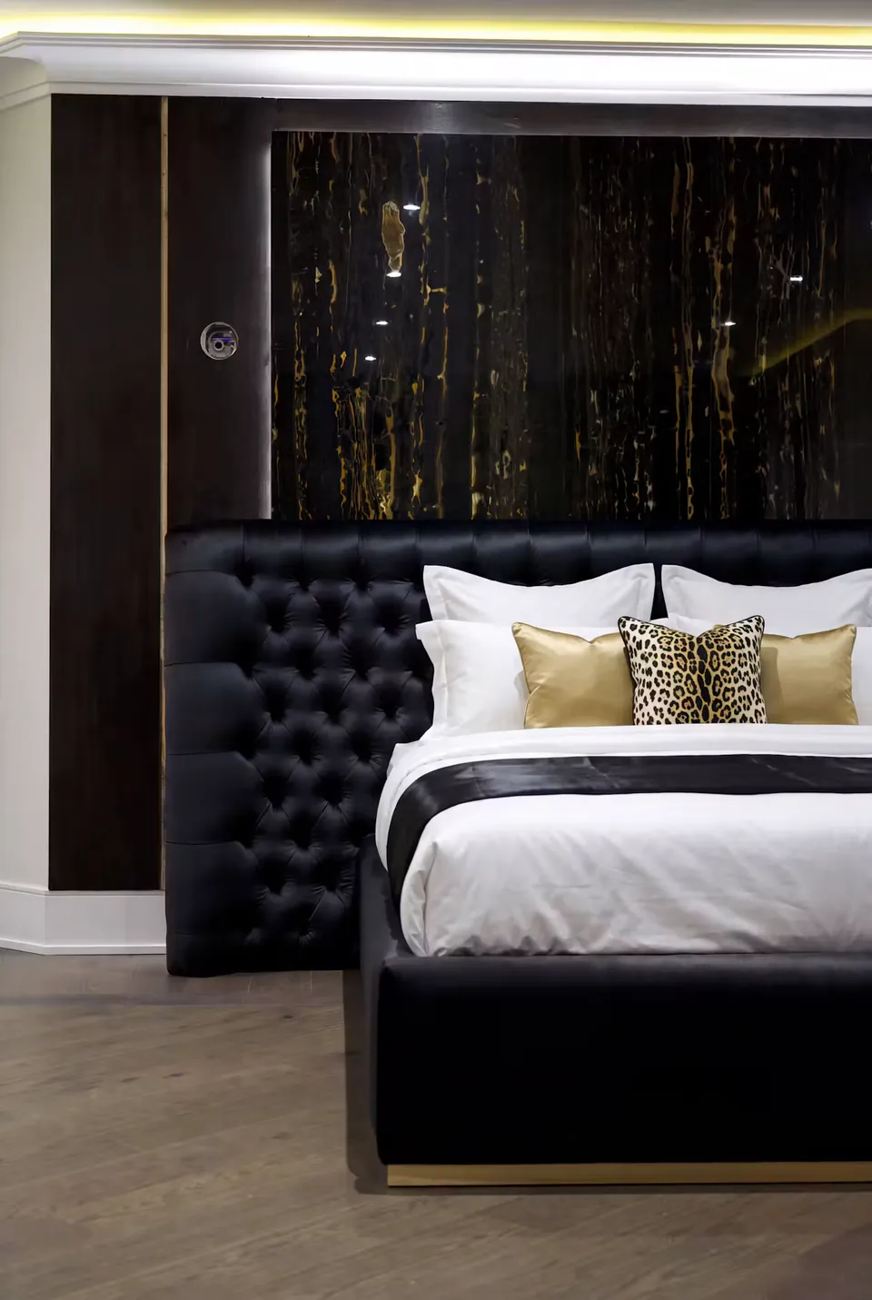 Angled view of the black tufted headboard and smooth black footboard.