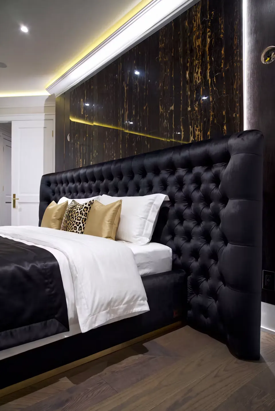 Side detail of black button tufting beneath the glossy dark wall.