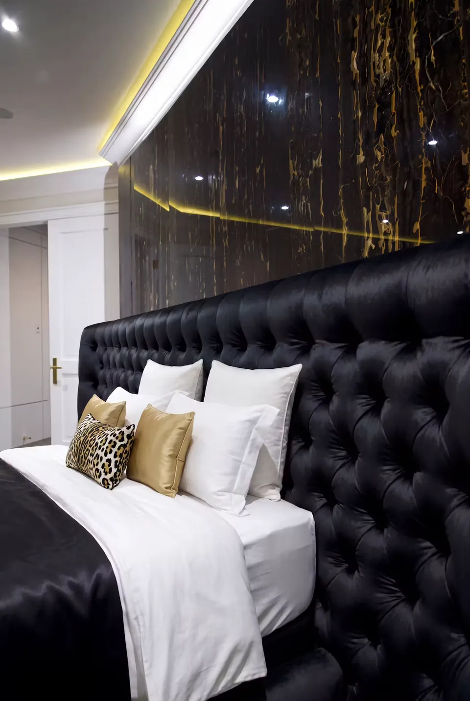 Close side view of deep black button tufting and pale pillows.