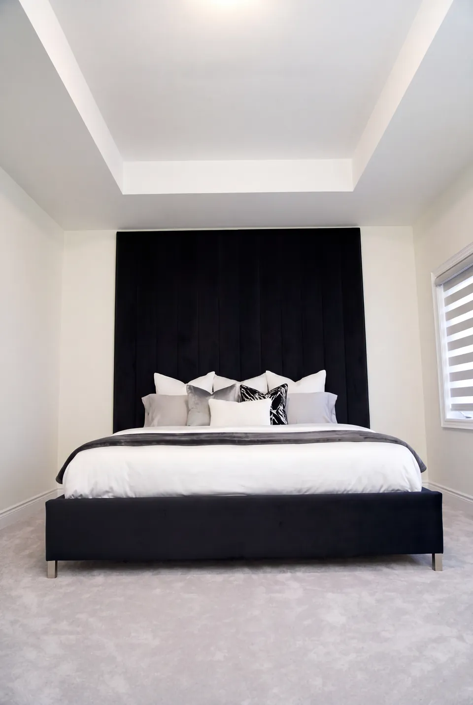 Full front view of a black upholstered bed beneath tall black vertical wall channels.