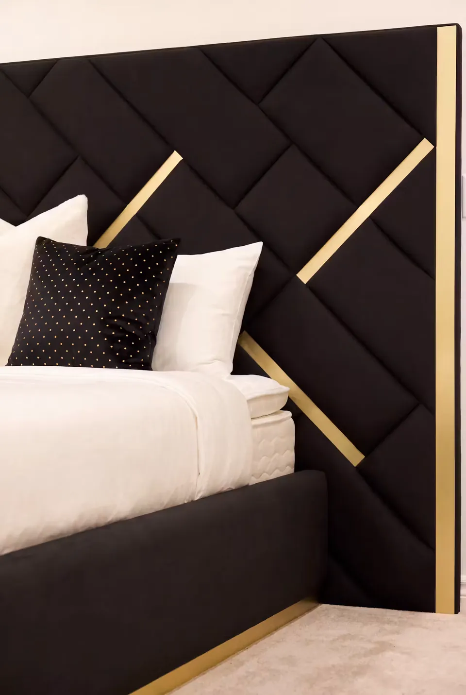 Close view of white bedding against black diagonal headboard panels.