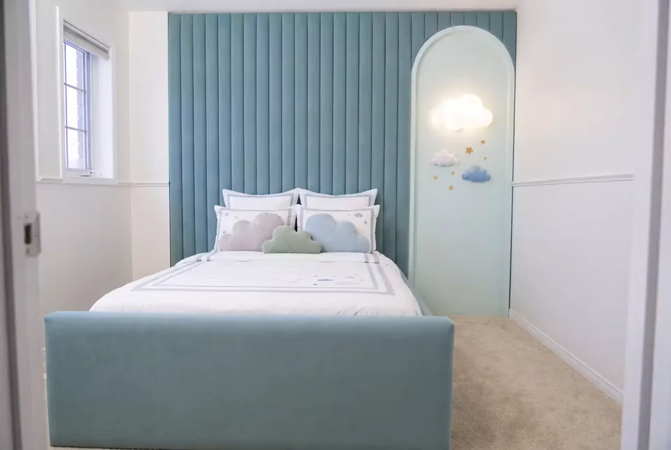 Blue upholstered children's bed with vertical panels and a rounded cloud alcove