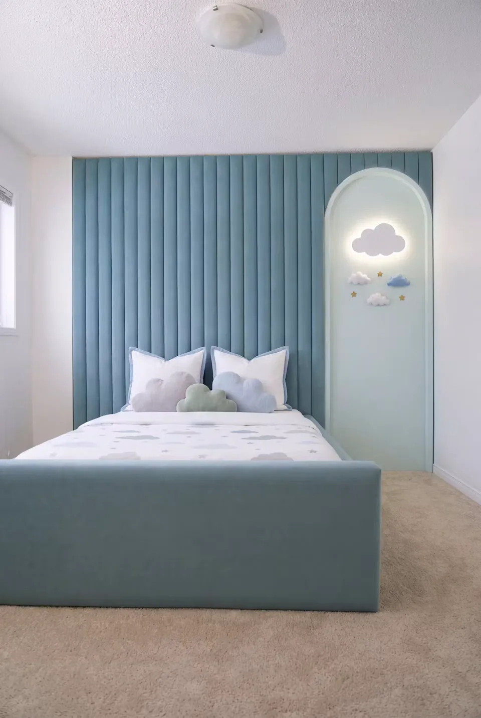 Full view of the compact blue bed and channelled wall with a cloud light