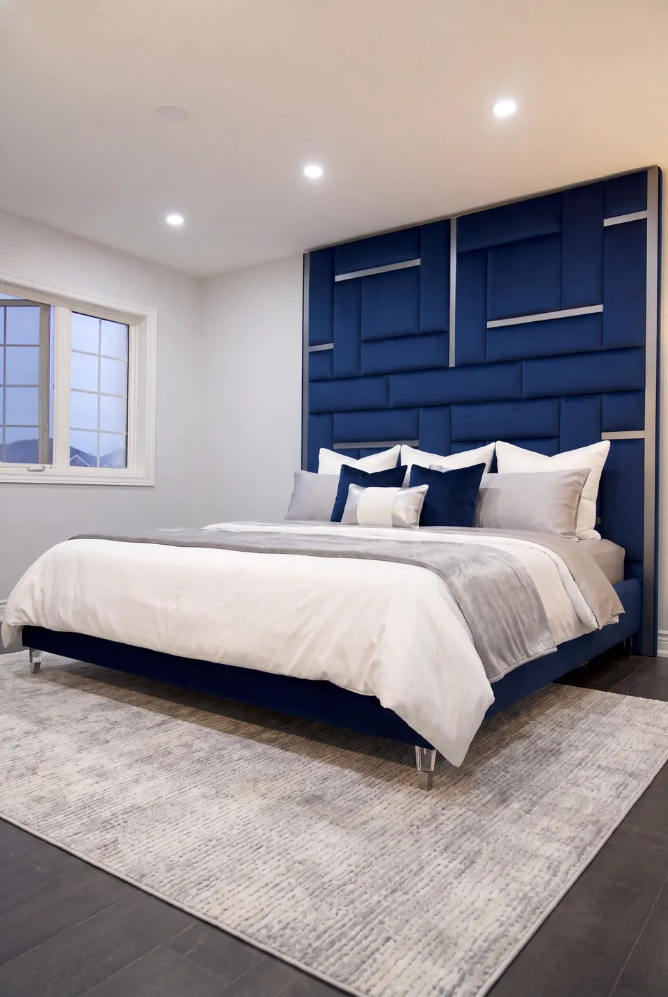 Full view of a blue upholstered bed and geometric blue wall panels beside a window.