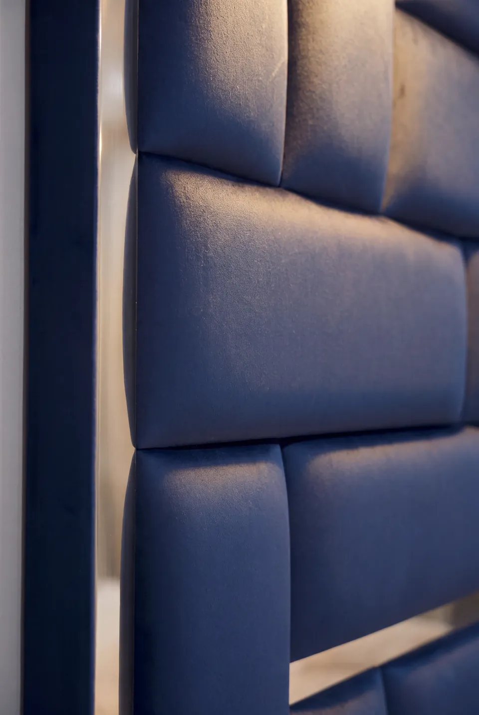 Detail of intersecting blue padded panels and a narrow gold strip.