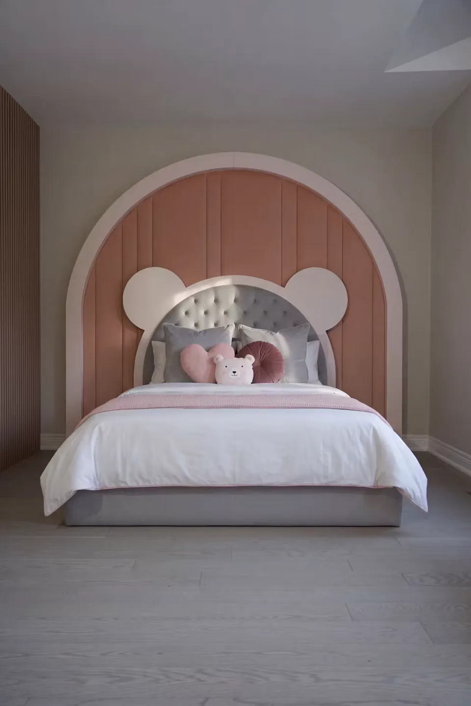 Full front view of the custom bed beneath the blush arch and bear-shaped headboard