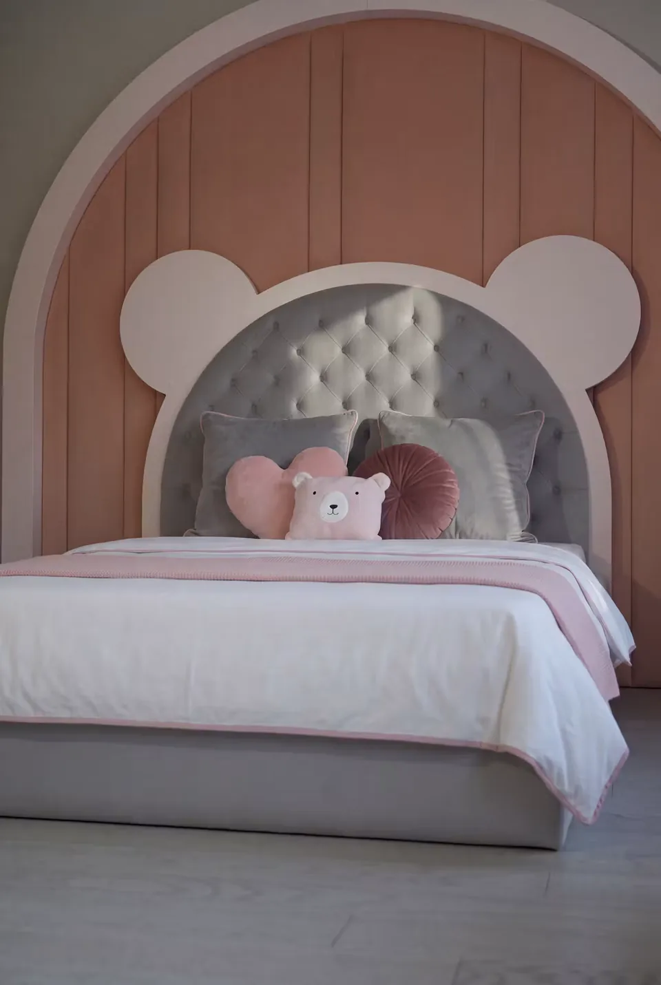 Closer front view of the grey buttoned bear headboard and pale frame
