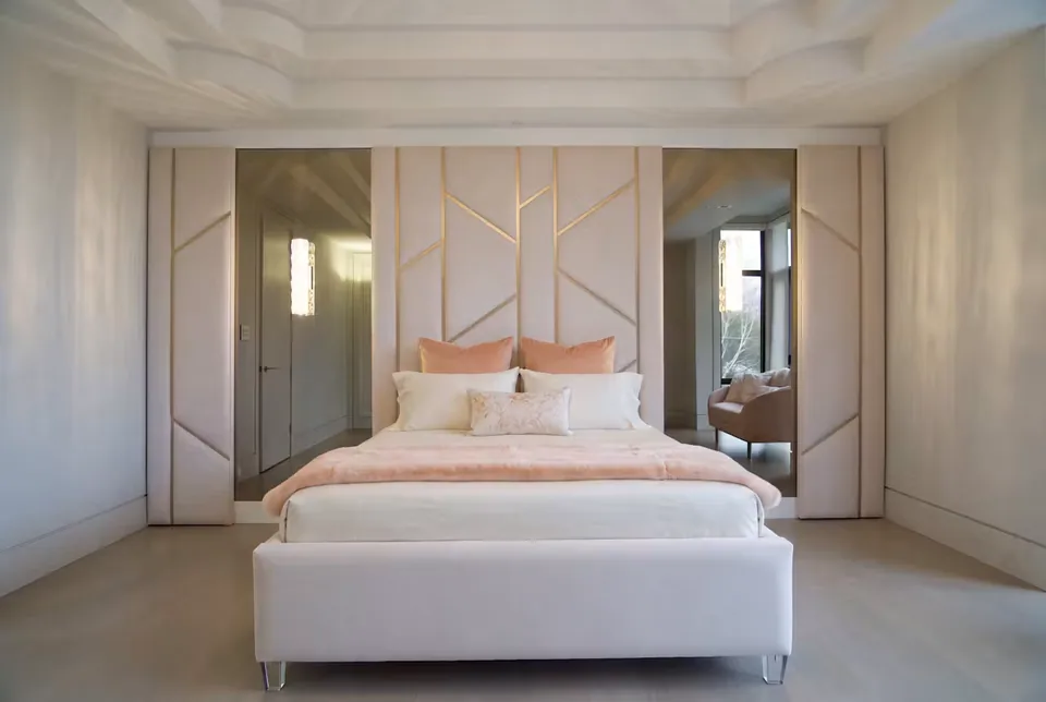 Front view of the bed, gold-accented padded wall and mirrored sides