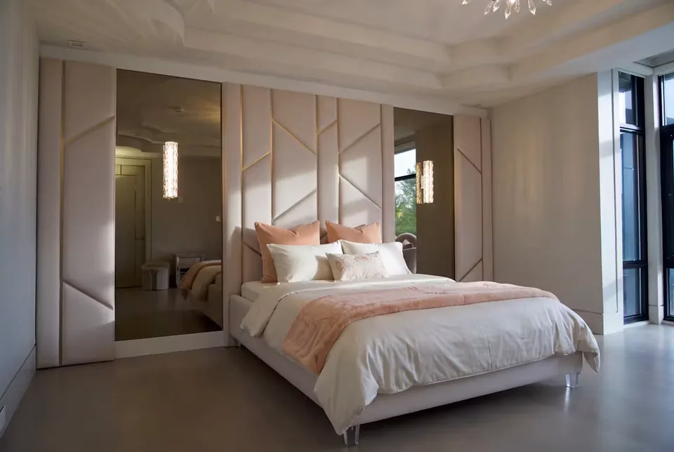 Angled view of blush panels and mirrors extending beside the bed