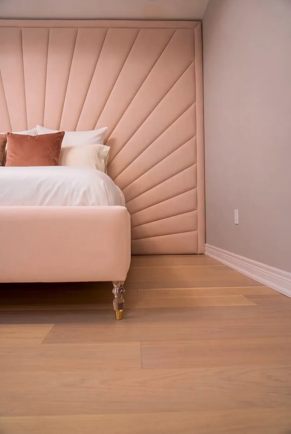 Close view of blush headboard rays and a rounded upholstered footboard
