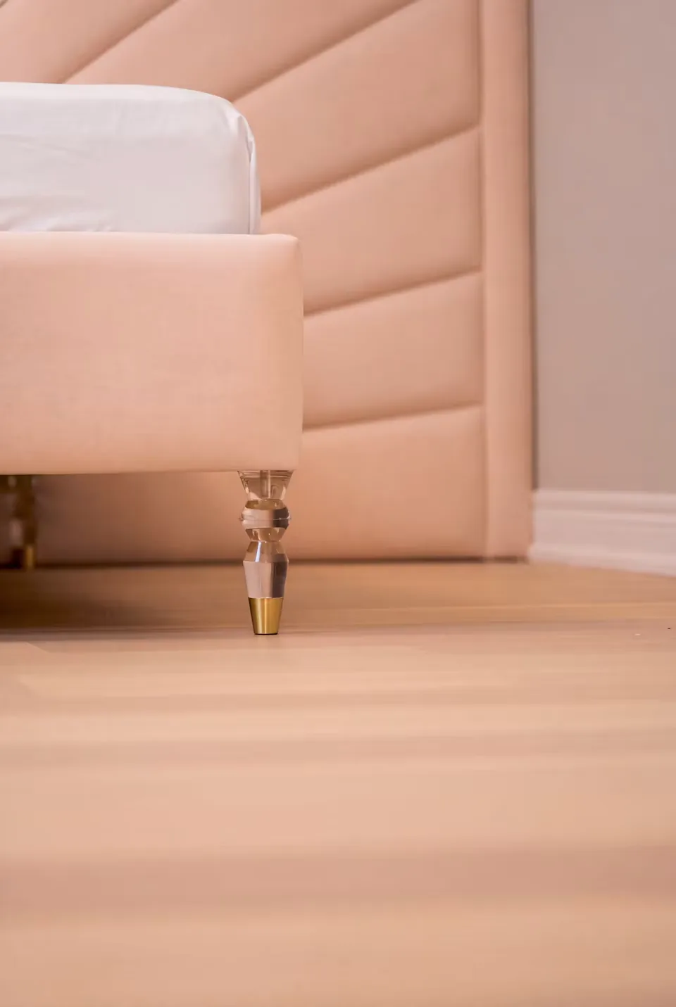 Low view of the pink upholstered footboard and its small decorative leg