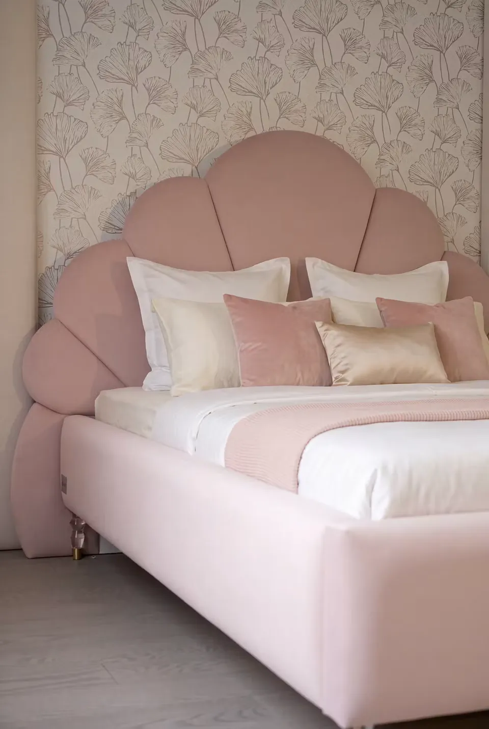 Angled view of the blush petal headboard and smooth upholstered frame.