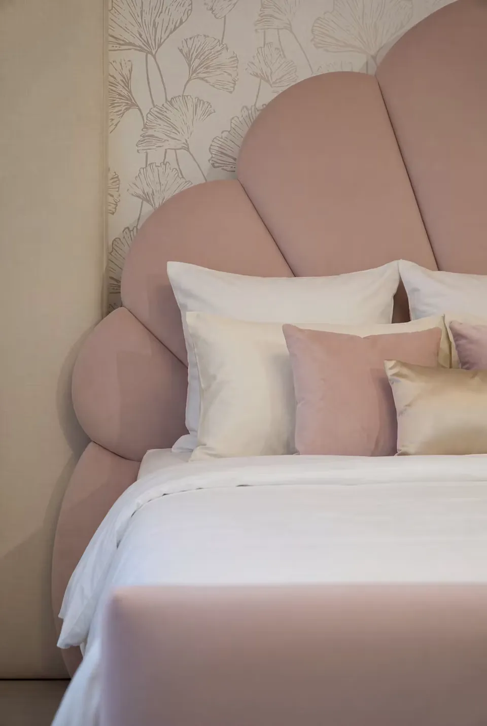Detail of the rounded blush headboard panels and white pillows.