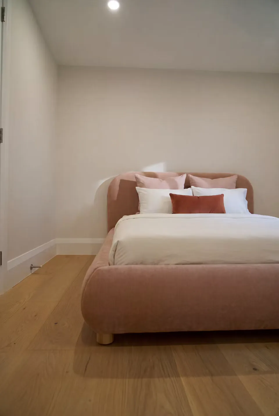 Front room view of the blush bed and low rounded headboard
