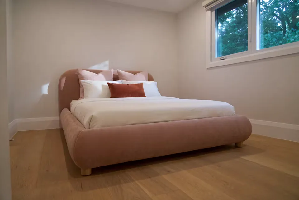 Wide angled view of the blush upholstered frame beneath the high window