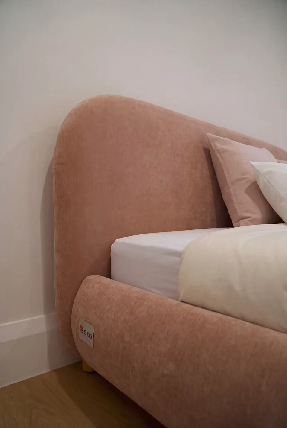 Close view of the rounded blush headboard and frame corner