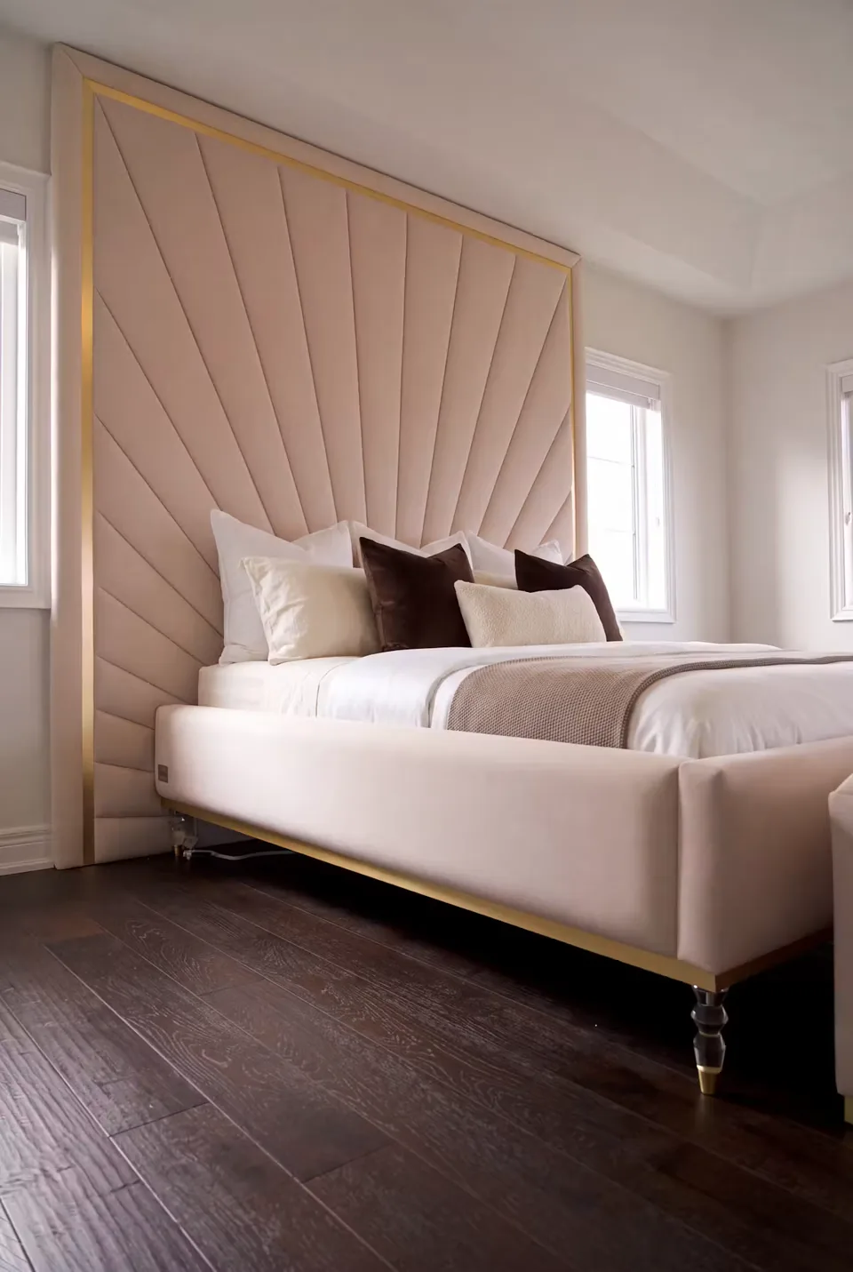 Full angled view of the blush bed on clear feet with fan-shaped wall panels behind it.