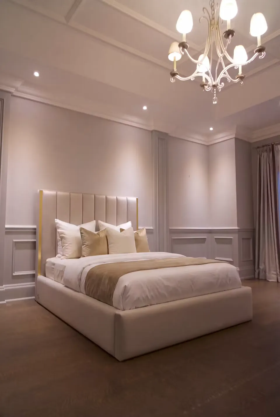 Full angled view of a champagne upholstered bed with a gold-edged channel headboard.