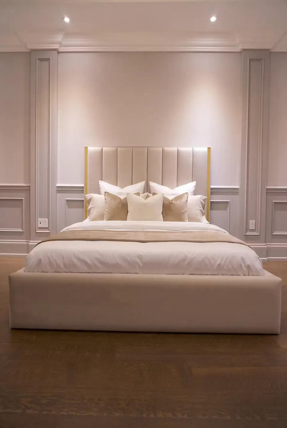 Front view of the champagne bed in a room with pale decorative wall mouldings.