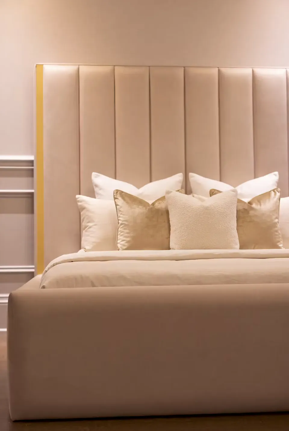 Detail of the champagne footboard and gold-edged vertical headboard channels.