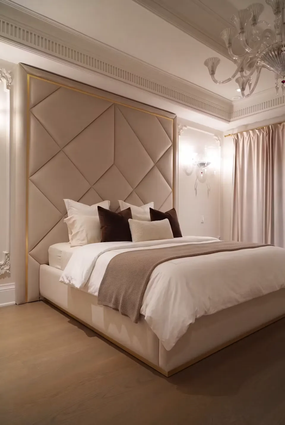 Champagne diamond-panel headboard and matching upholstered bed below a glass chandelier