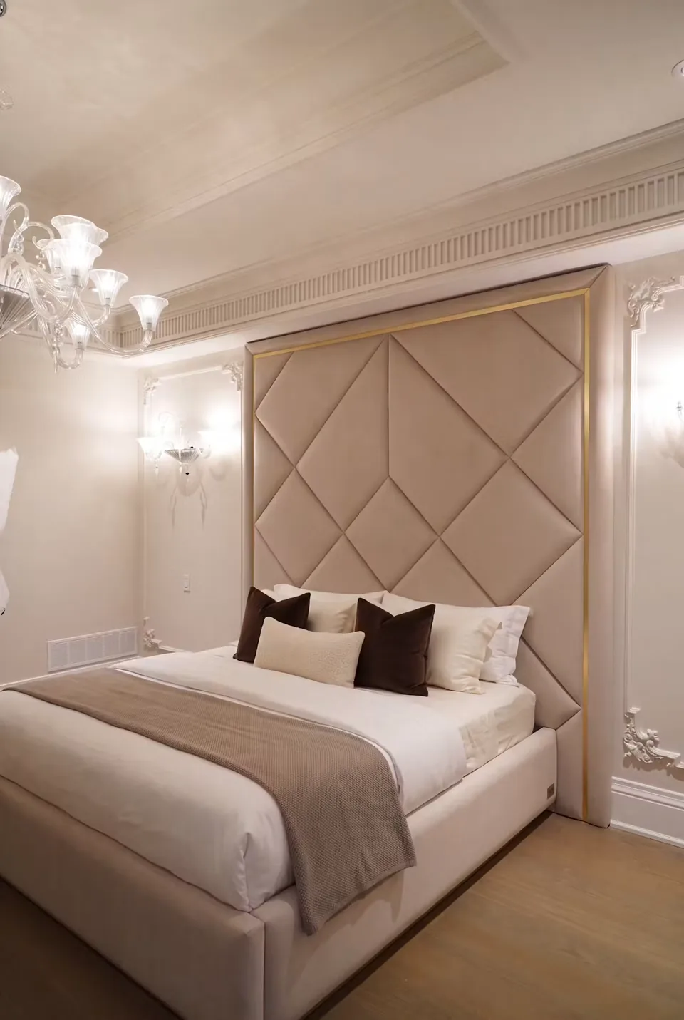 Angled view of a pale upholstered bed against a tall geometric headboard