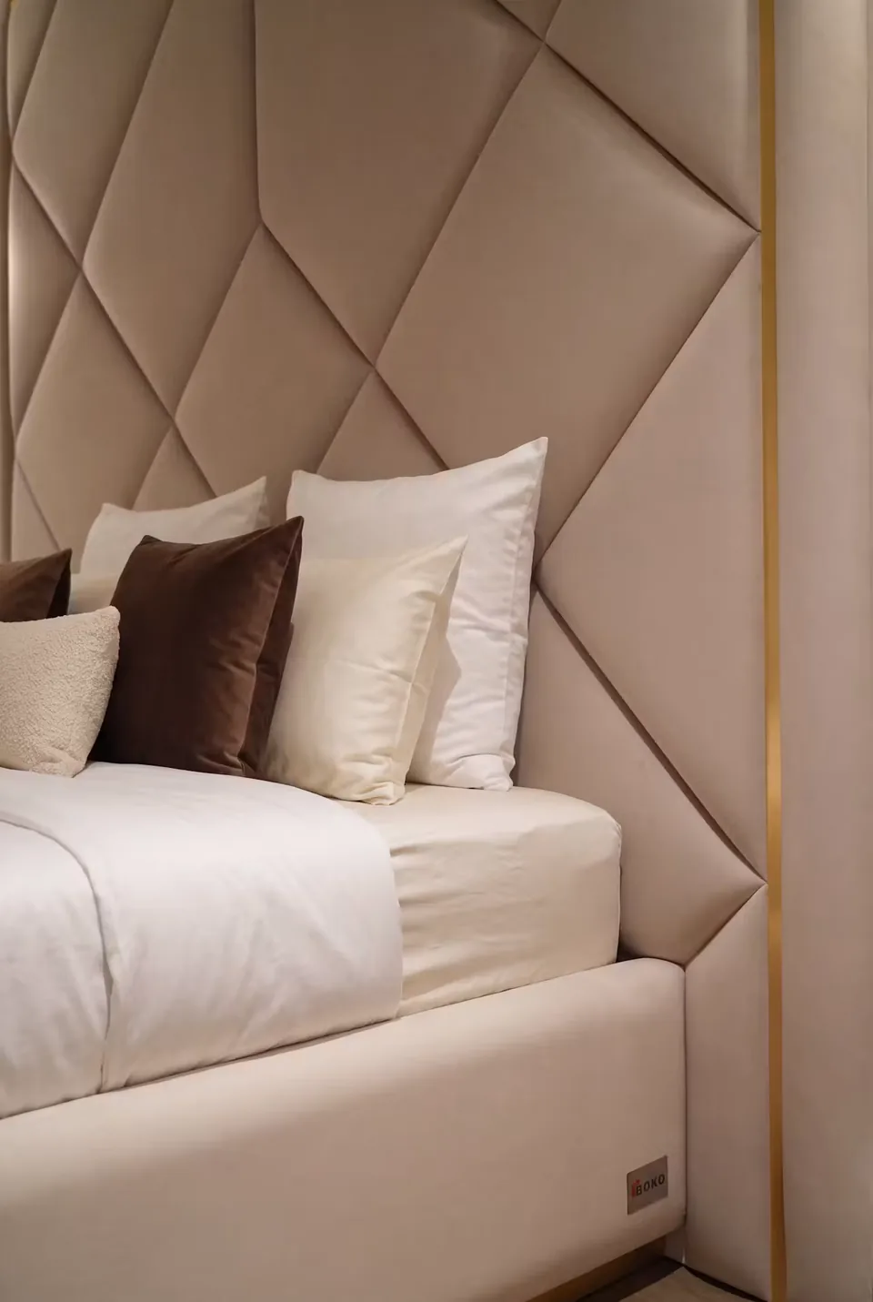 Detail of angled padded headboard seams beside white and brown pillows