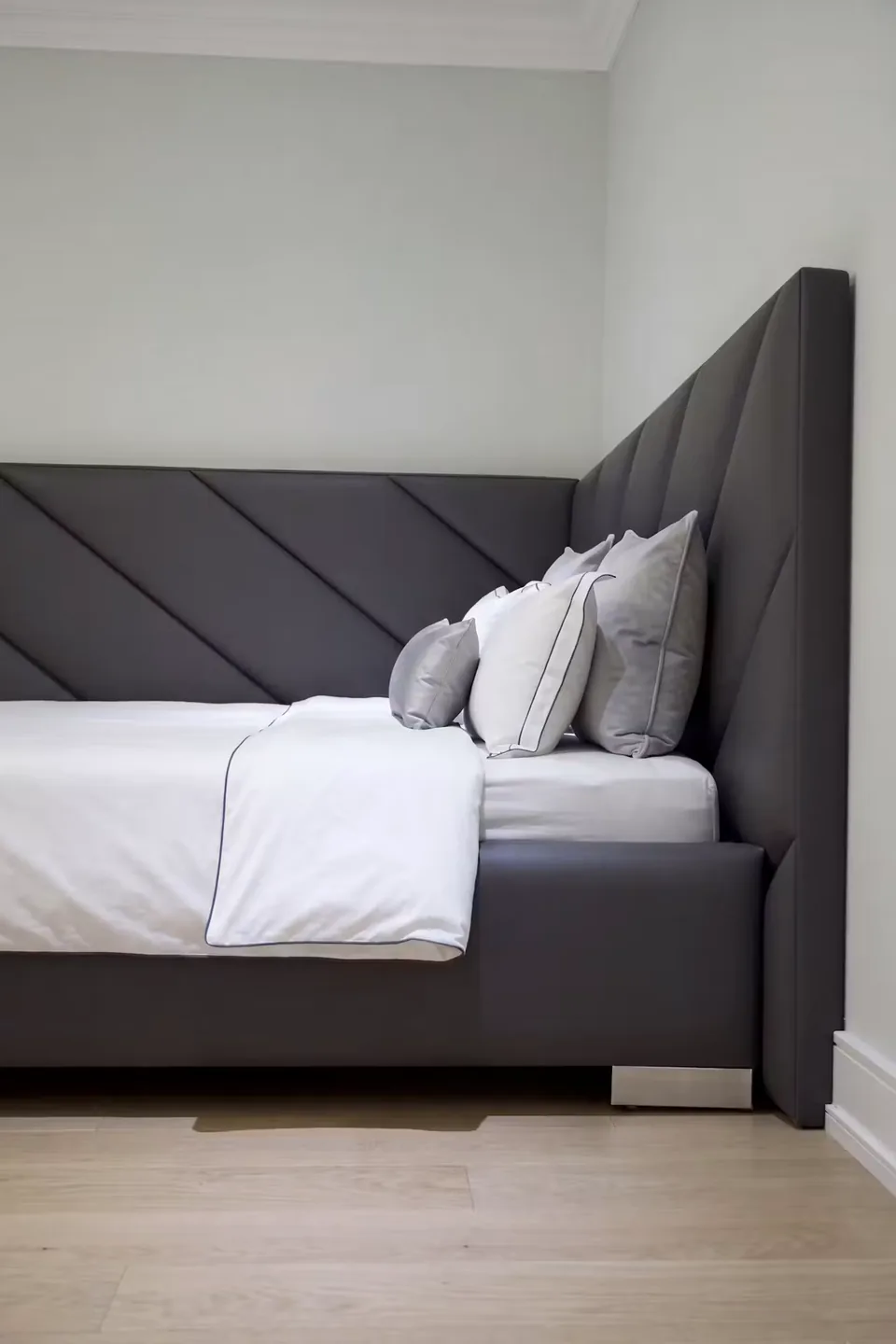 Portrait side view of the charcoal bed and angled upholstered corner