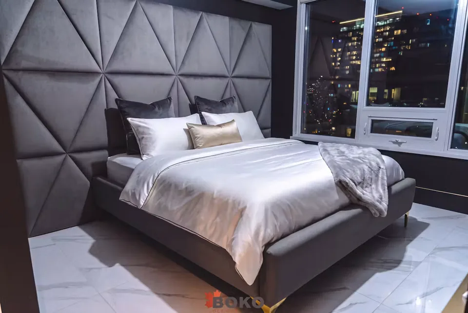 Wide view of the dark bed beside the windows and faceted wall