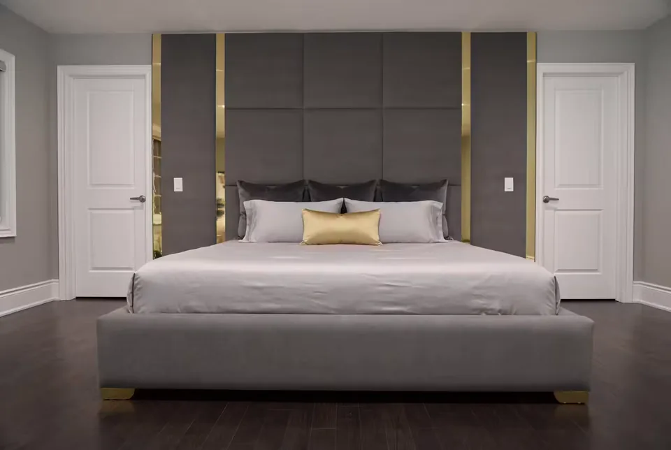 Full grey bed beneath a charcoal panel grid with tall gold bands