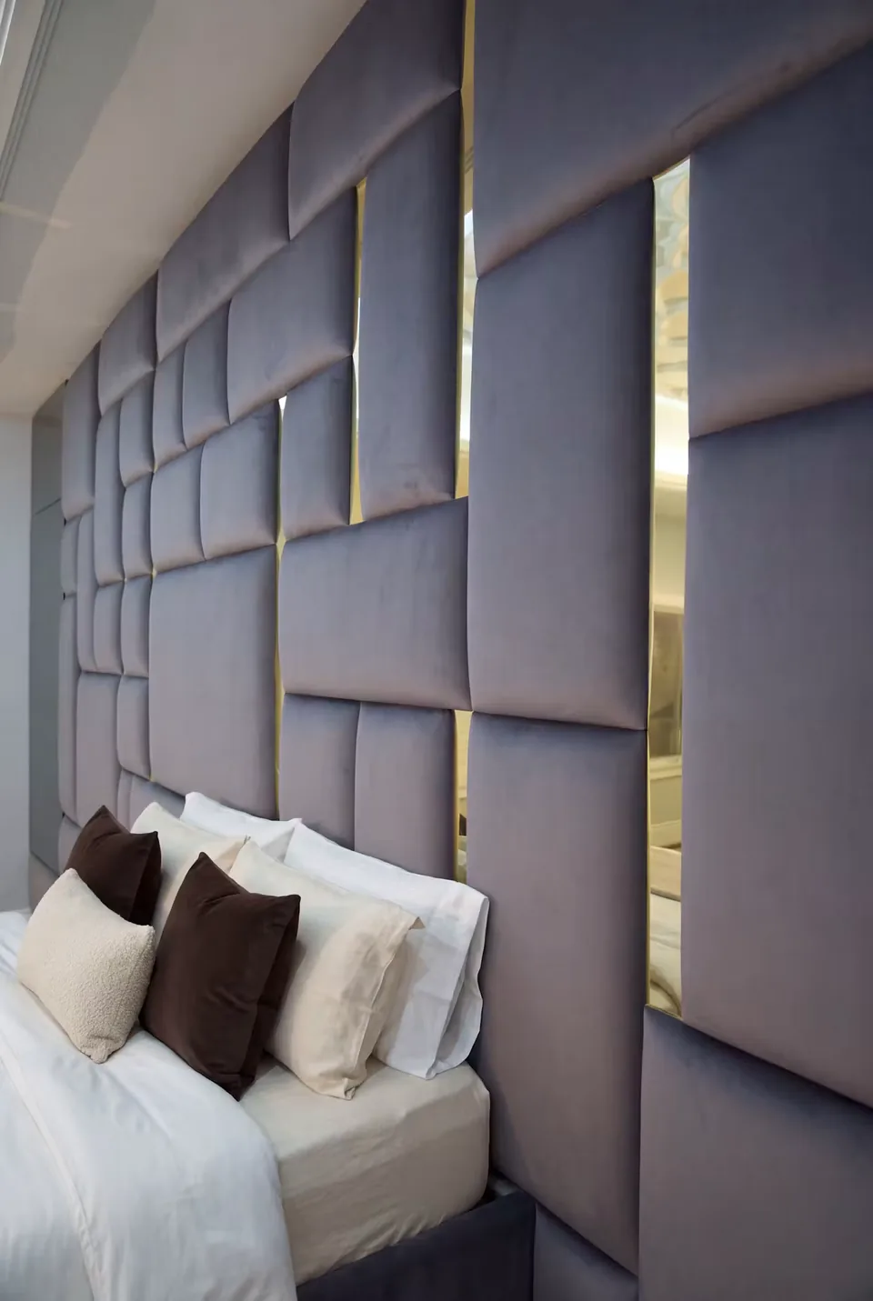 Close angled view of charcoal upholstered rectangles and short gold divisions above the pillows.