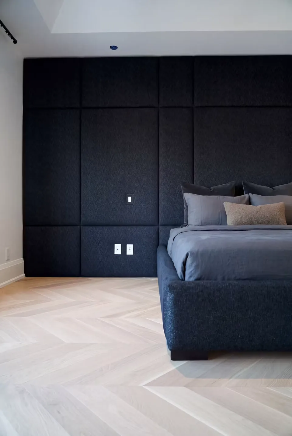 Side view of the charcoal padded wall beside the dark bed