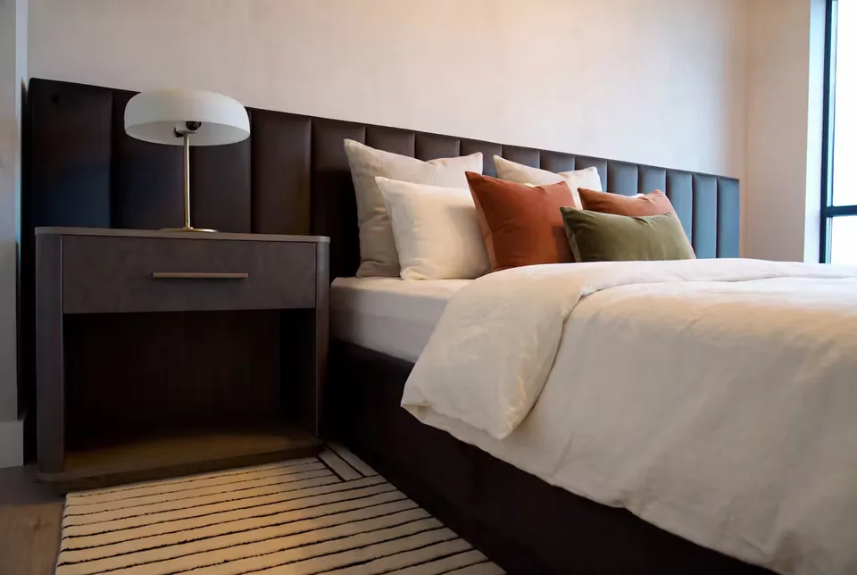 Close view of the charcoal upholstery beside the bedside lamp