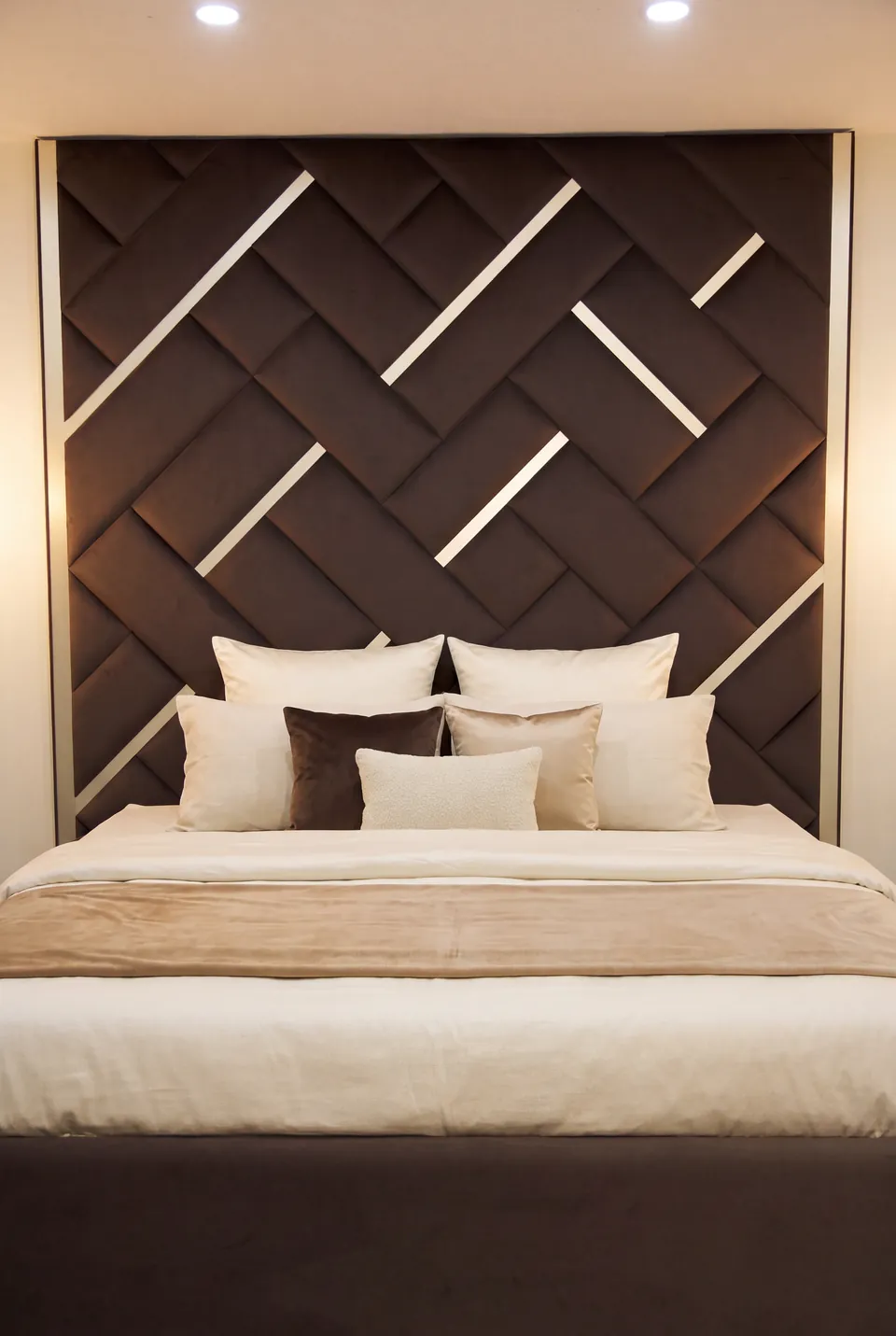 Front view of white bedding against interlocking brown upholstered wall panels.