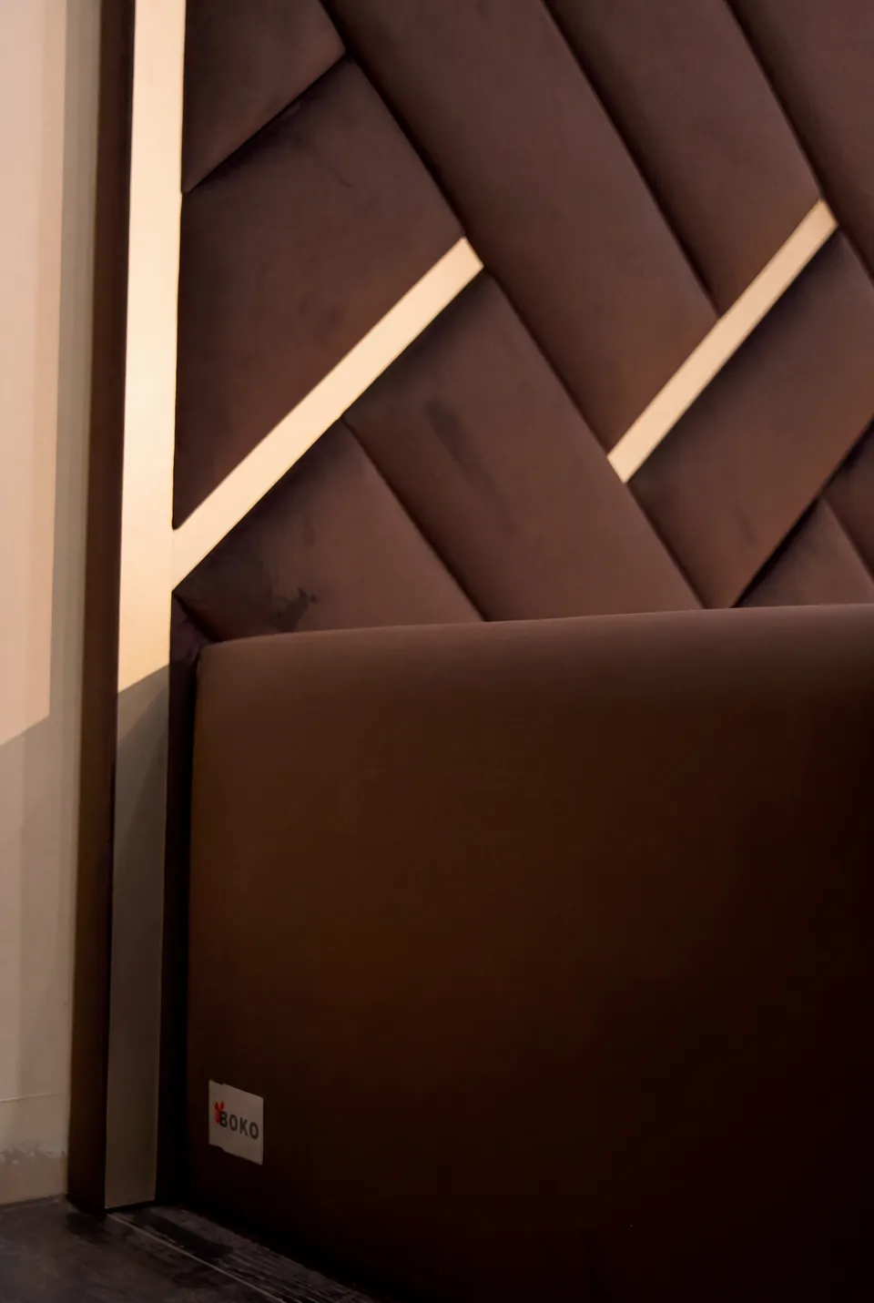 Close view of brown padded panels, a gold accent and the upholstered bedside edge.