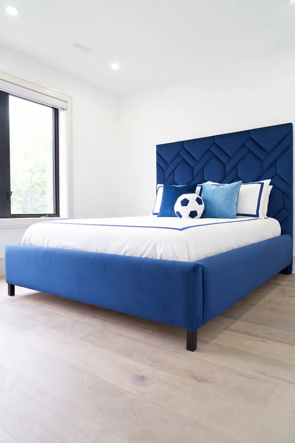 Full angled view of the blue bed and woven geometric headboard