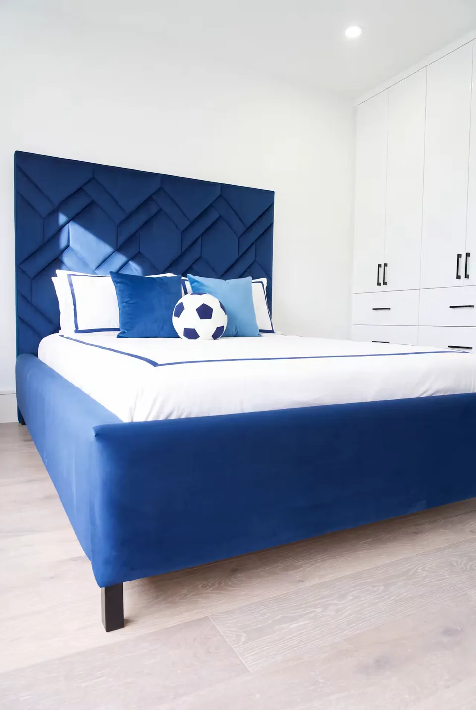 Wide view of the cobalt bed frame beside white cabinetry